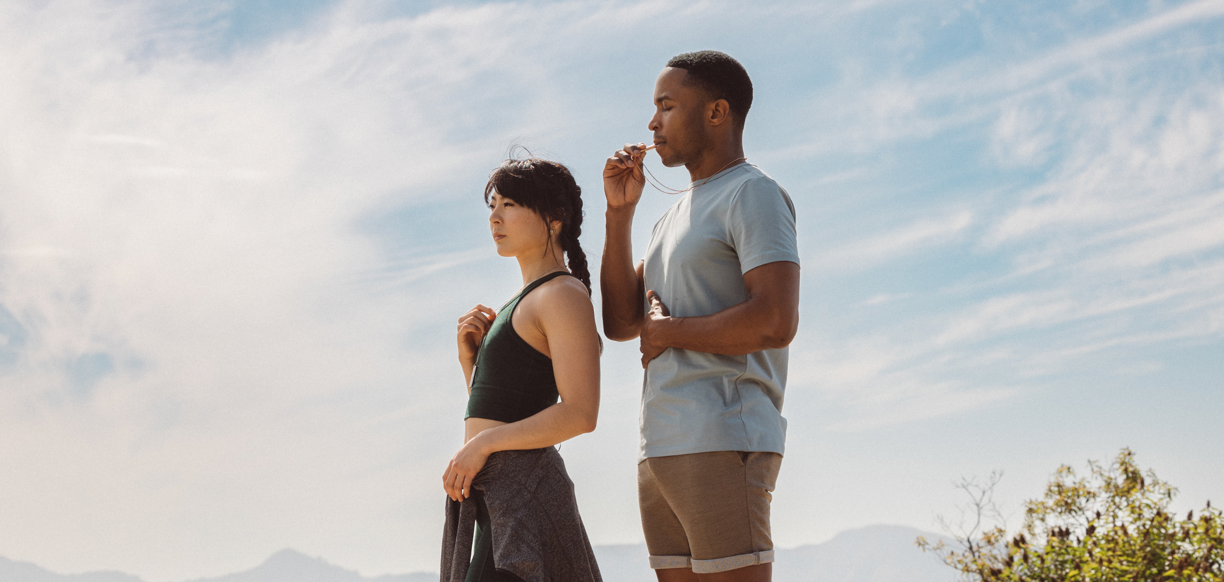Man practicing slow breathing through the Komuso Classic Shift while a woman wearing the breathing necklace looks up at the sky during a calming moment.