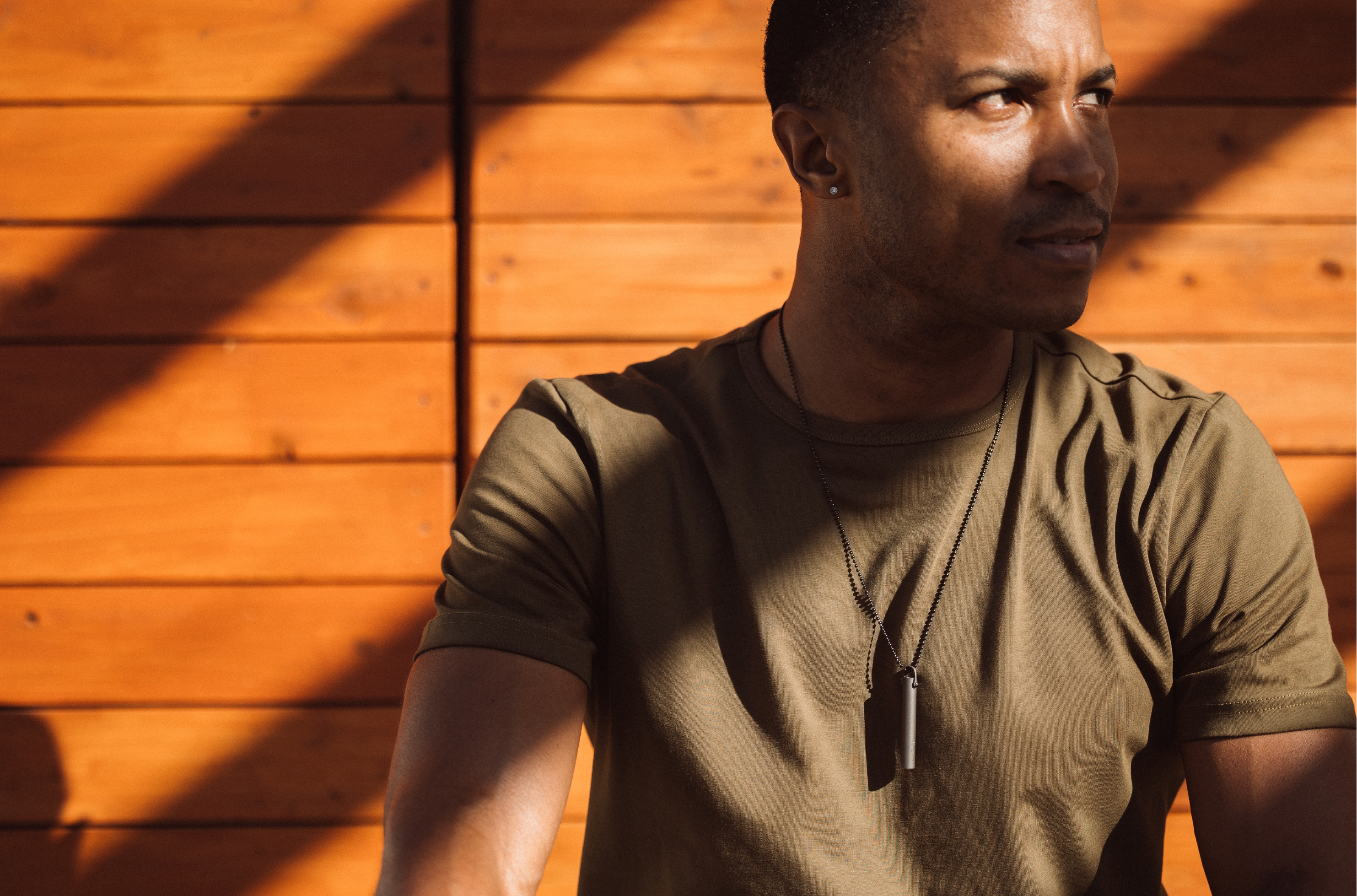 Man wearing the Komuso Classic Shift breathing necklace while sitting and reflecting, practicing calm breathing for stress and burnout.